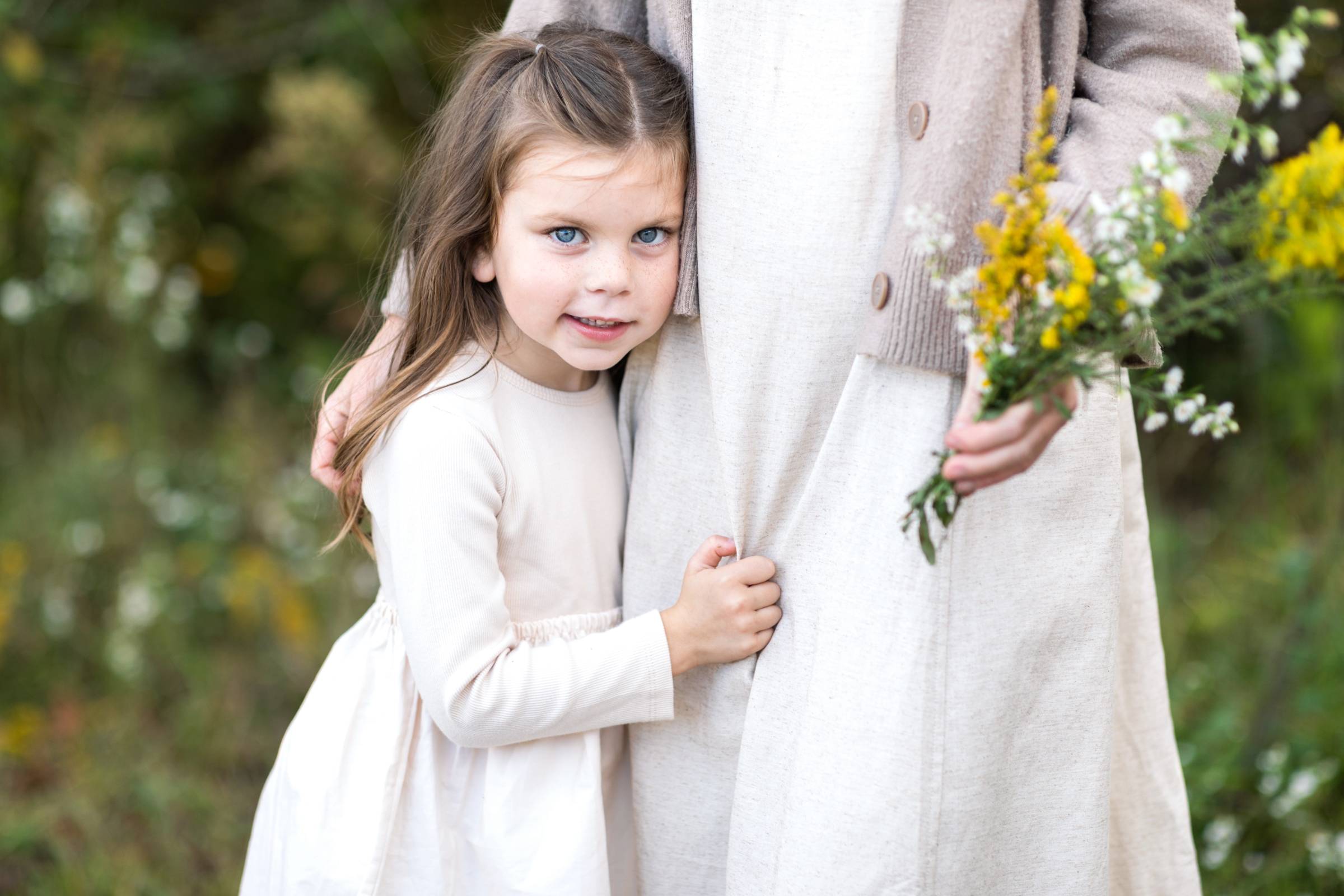 Mother and Daughter standing together in field with flowers daughter is holding mother and smiling